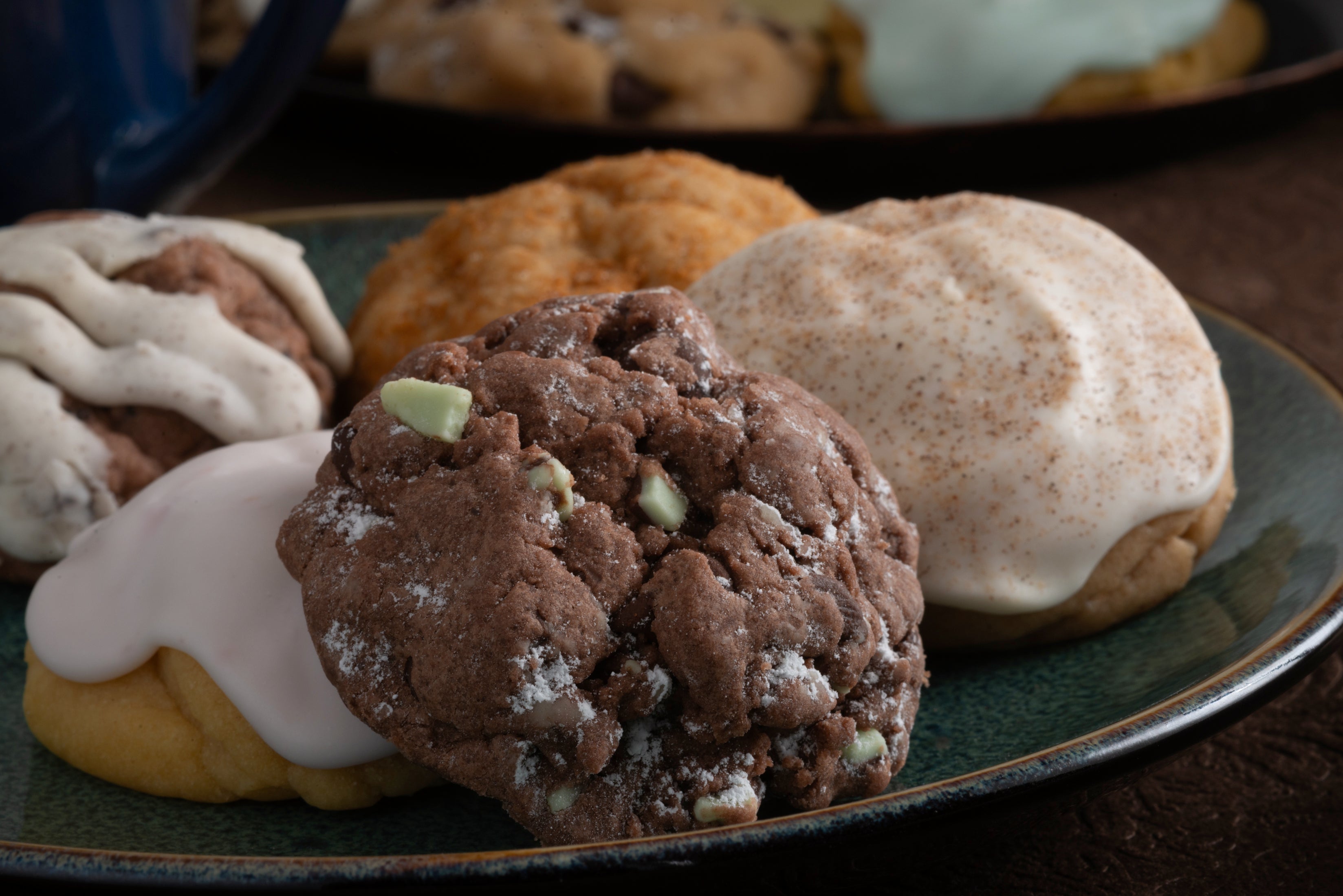 An assortment of our handcrafted, gourmet cookies, featuring our seasonal flavors: Chocolate Brownie Grenade, Violet, and Amoreo cookies.