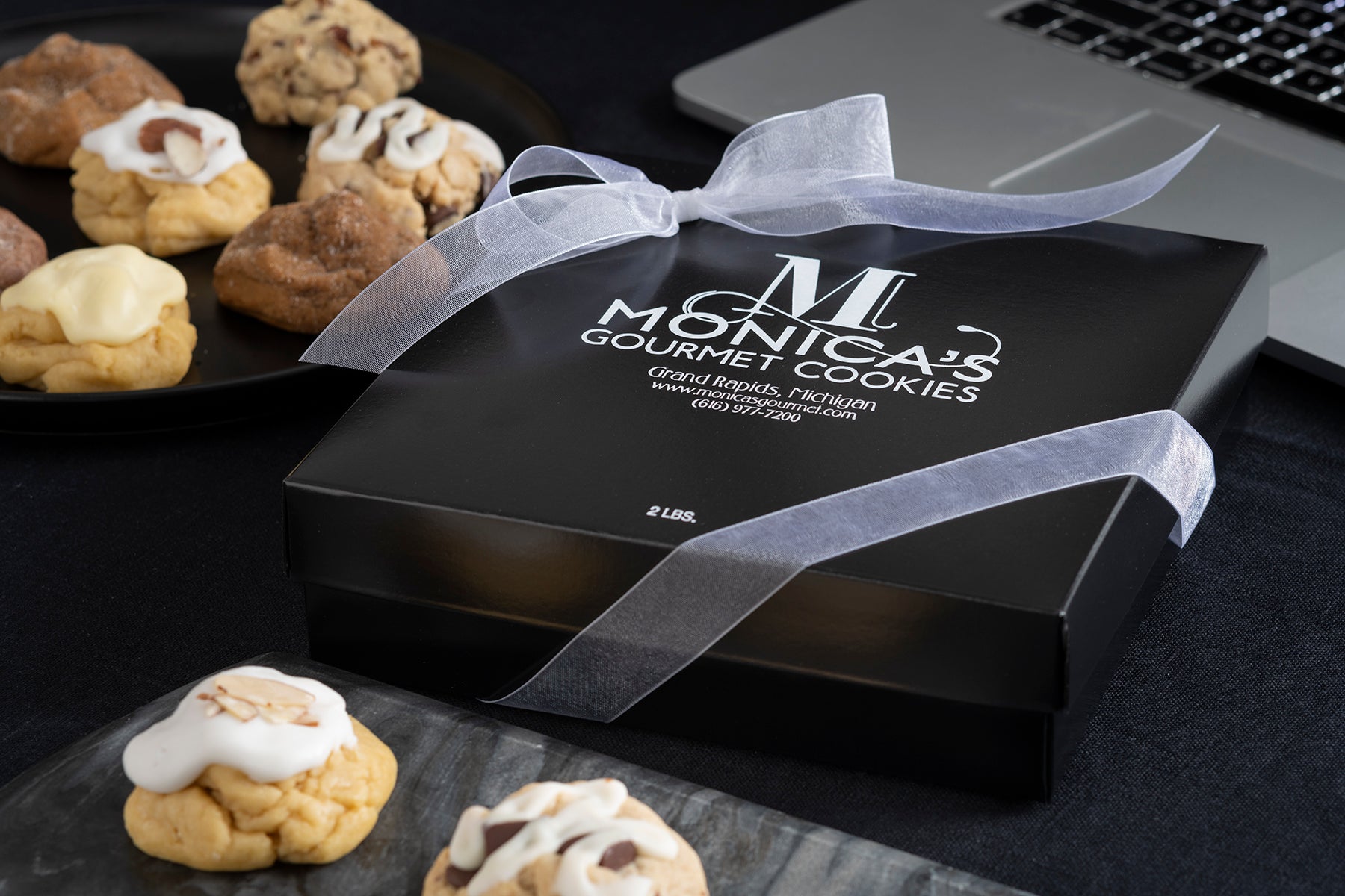 A Monica's Gourmet gift box with an arrangement of cookies, featuring Iced Almond, Caramel Rock, and Iced Lemon.